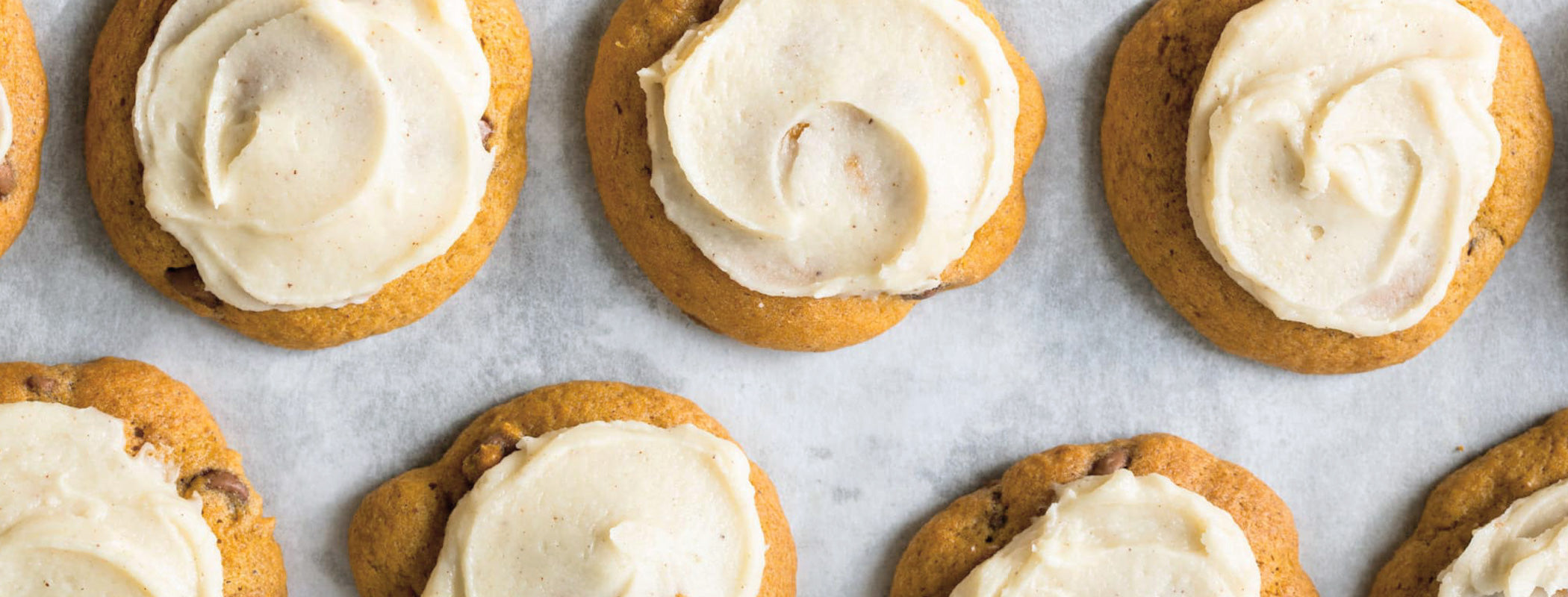Pumpkin chocolate chip cookies with cream cheese frosting on rack