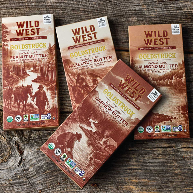 Four flavors of Goldstruck bars in their boxes on a wooden table top